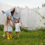 A mother stand underneath a clothesline with her two children on a summer day.