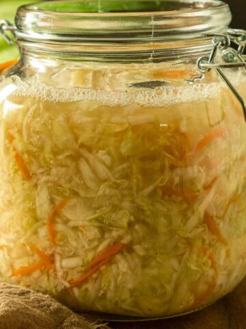 A large jar full of homemade fermented green cabbage sauerkraut.
