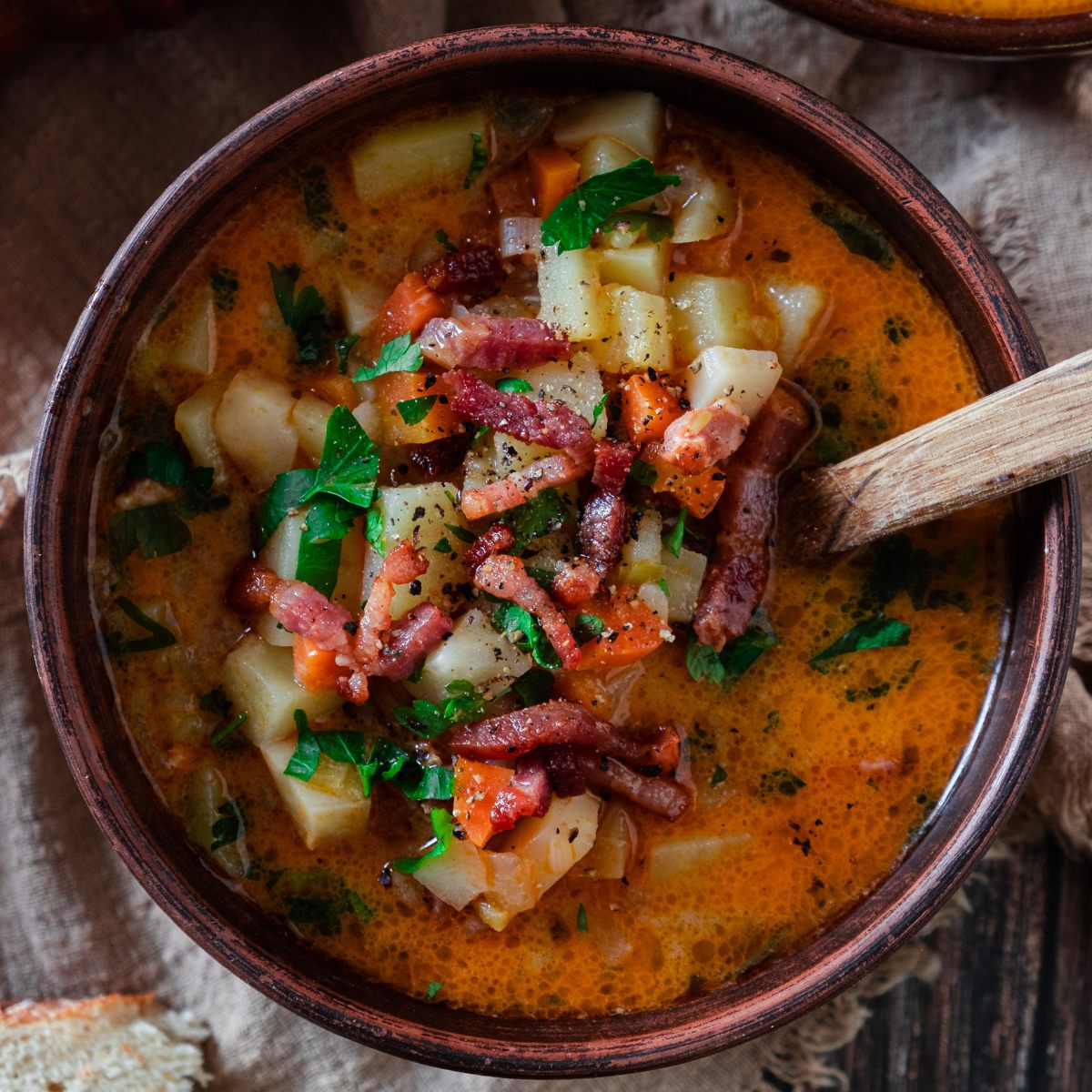 A bowl full of chunky, creamy German potato soup with lots of veggies and bacon.