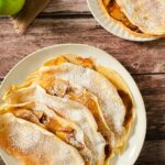 Pancakes stuffed with cooked, spiced apple slices and covered in powdered sugar.