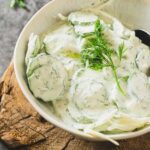 Creamy German cucumber salad in bowl full of fresh dill.