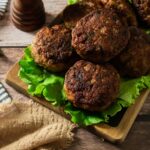 A pile of German frikadellen meatball patties on a bed of lettuce.