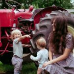 Jana Dziak and her two sons in front of a red tractor on a summer day.