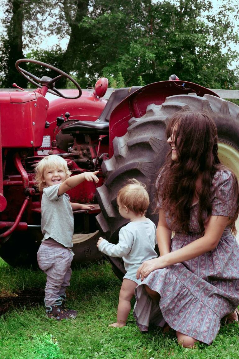 Jana Dziak and her two sons in front of a red tractor on a summer day.