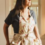 Me standing in my kitchen wearing a floral apron.