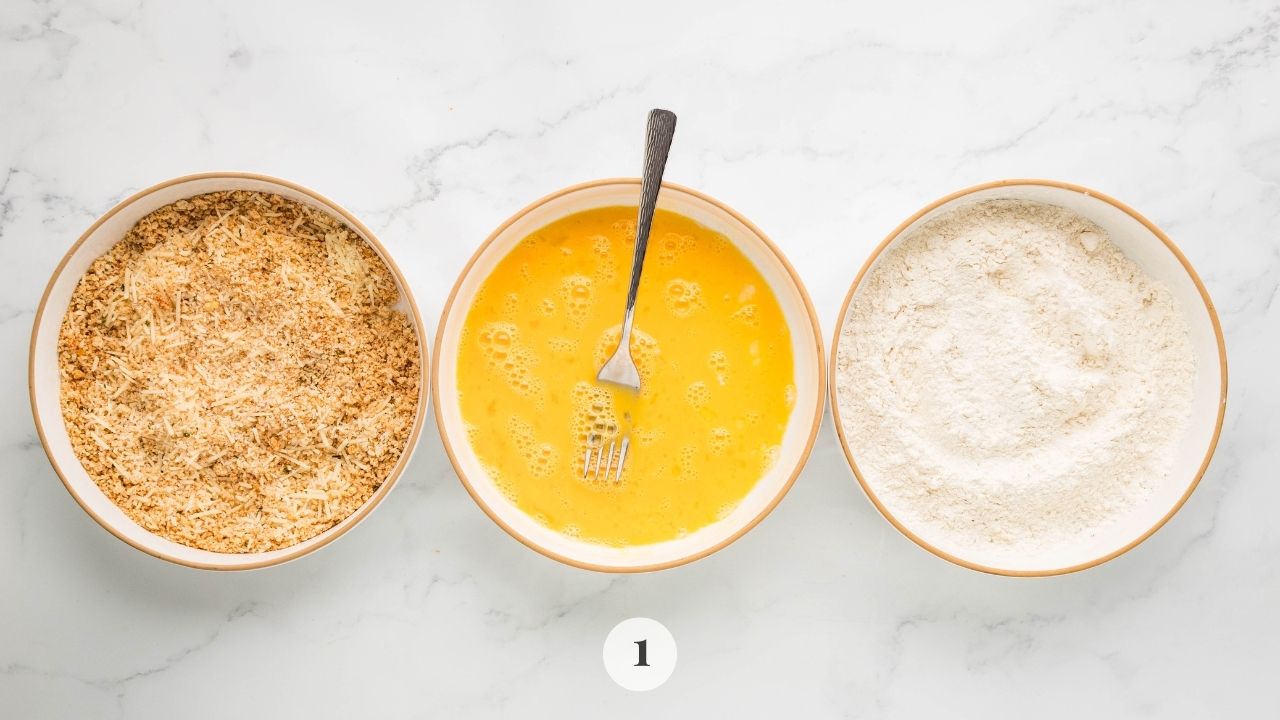 Three set of bowls containing breadcrumbs, egg, and flour.