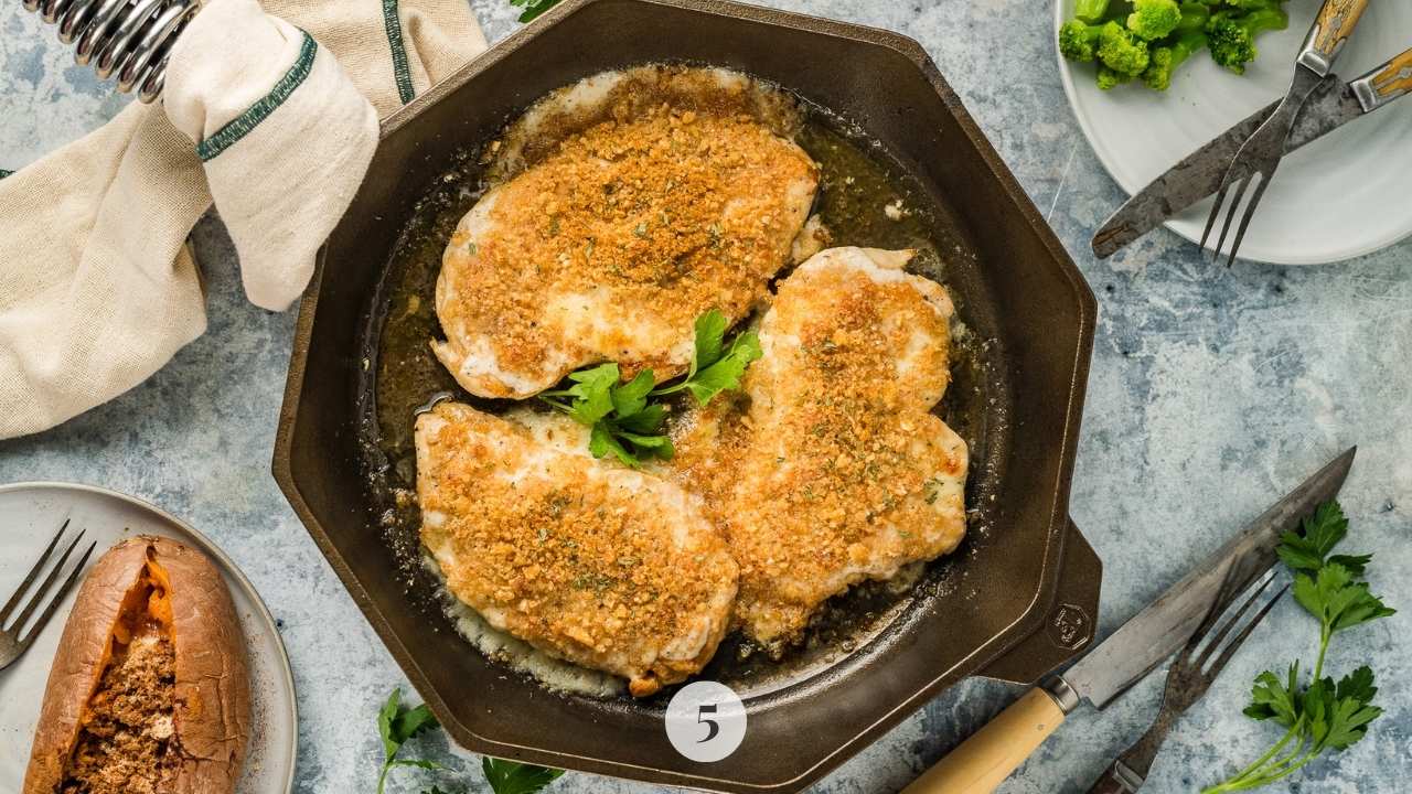 Chicken in the skillet topped with panko crumbs and parsley.