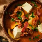 A bowl of pierogi soup in a rich tomato broth.