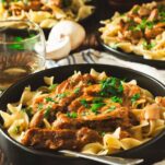 Beef stroganoff served in a bowl, with tender beef and creamy sauce over egg noodles, garnished with fresh parsley.