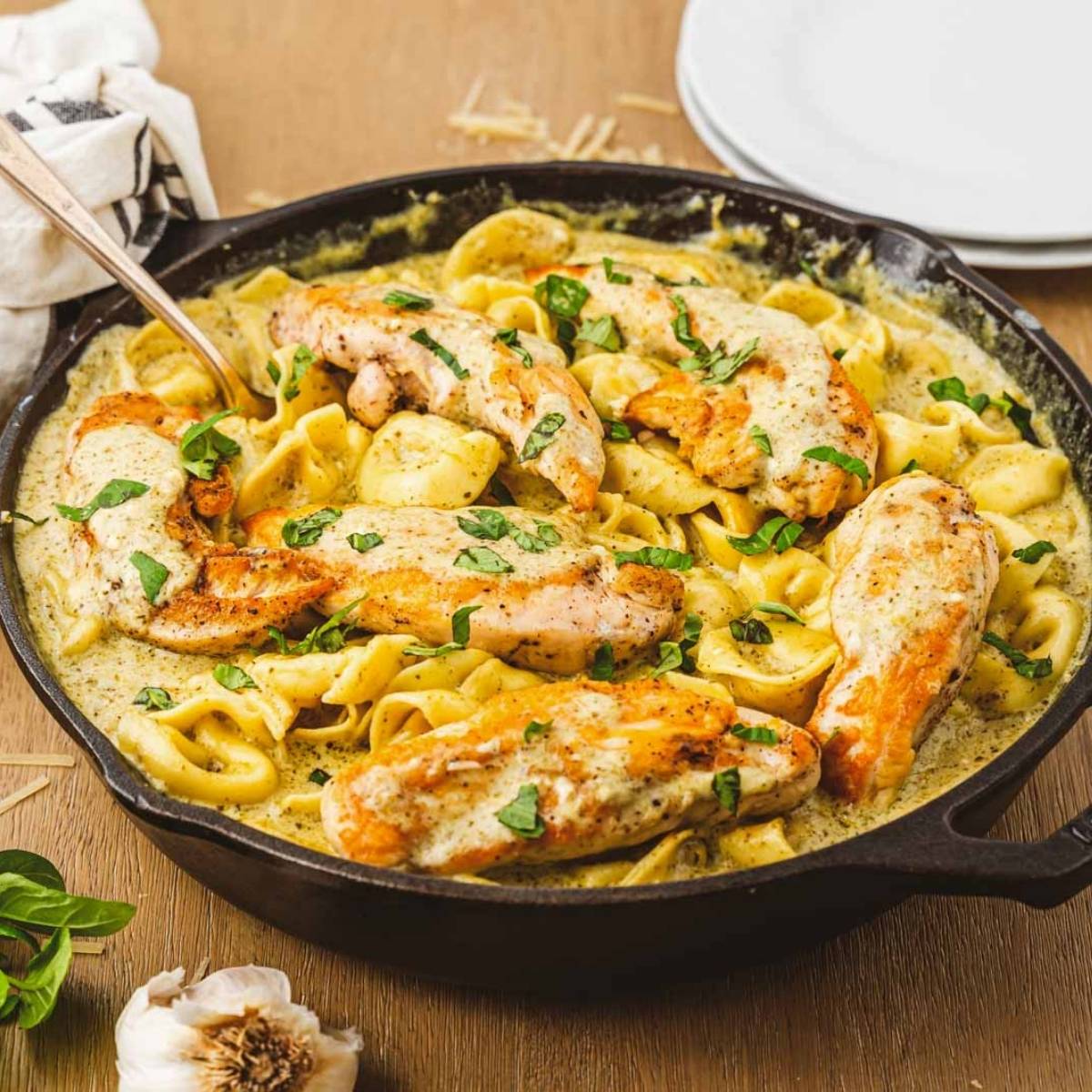 Seared chicken and cheese tortellini were coated in a creamy pesto sauce and served in a cast iron skillet, garnished with fresh basil.