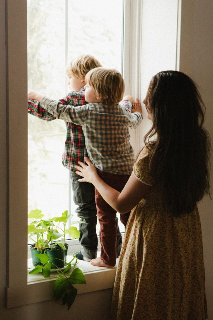 A woman with her two young boys at the window.