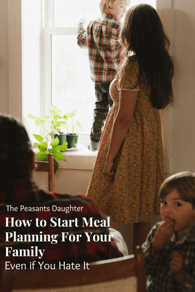 A woman with her two sons and husband at the dining room table getting ready to eat dinner.