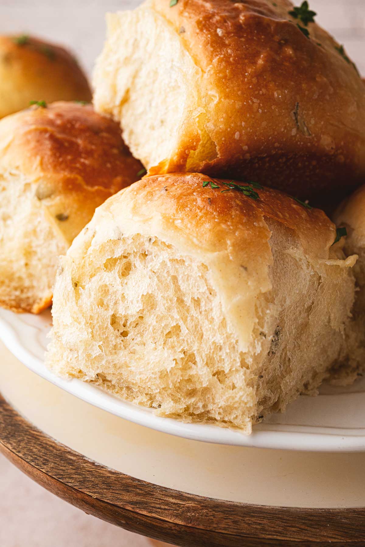 A platter of pillowy soft sourdough pull apart dinner rolls covered in a butter sauce infused with herbs.