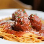 Saucy meatballs in red sauce served on top of spaghetti.