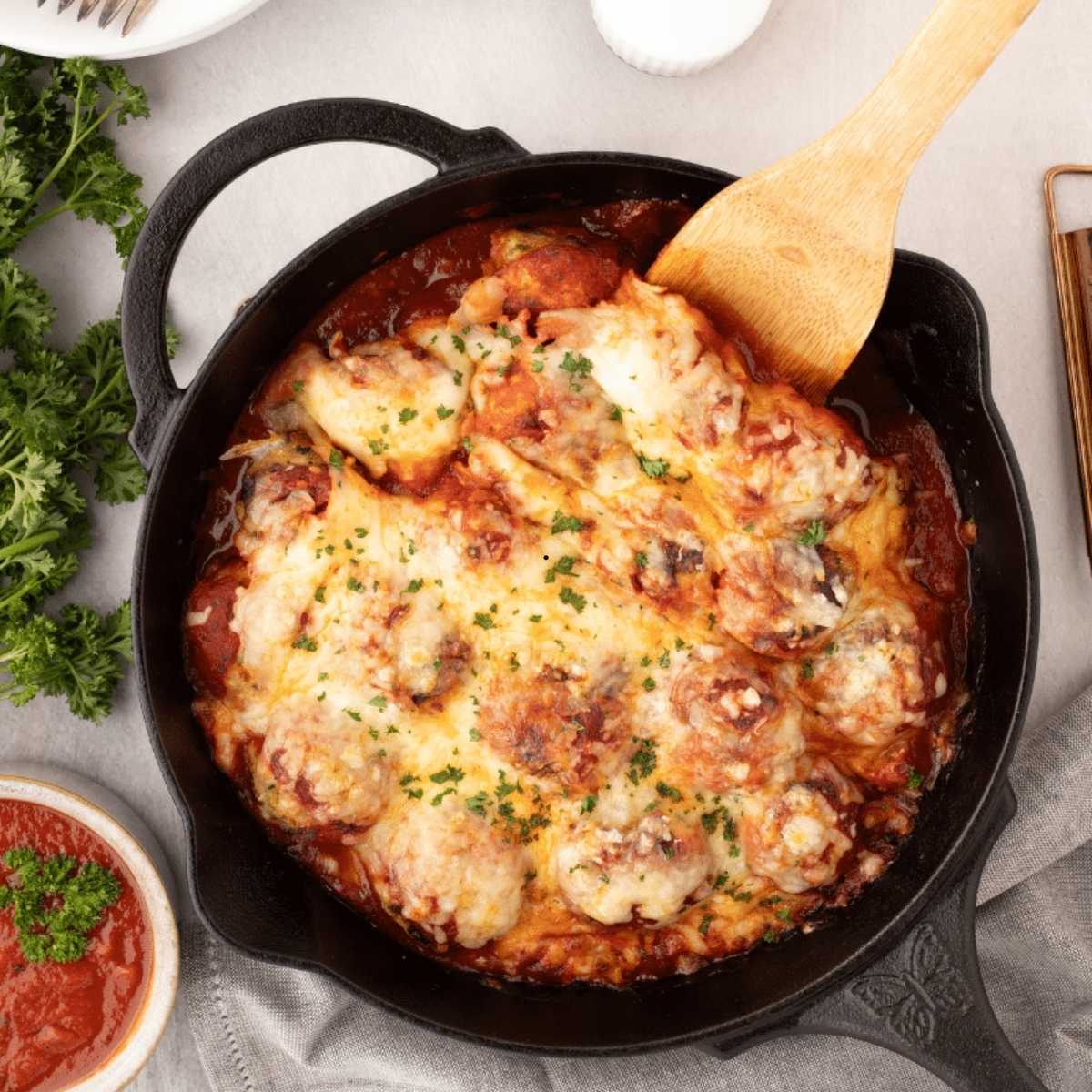 Chicken parmesan style meatballs made and served in a skillet.