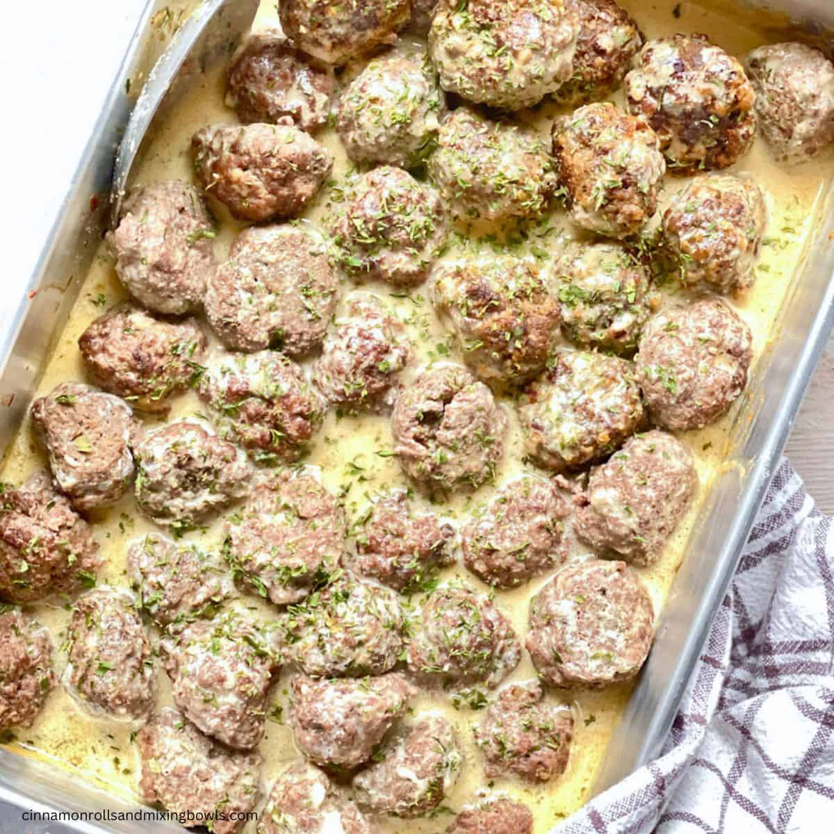 Saucy creamy meatballs on a baking tray.