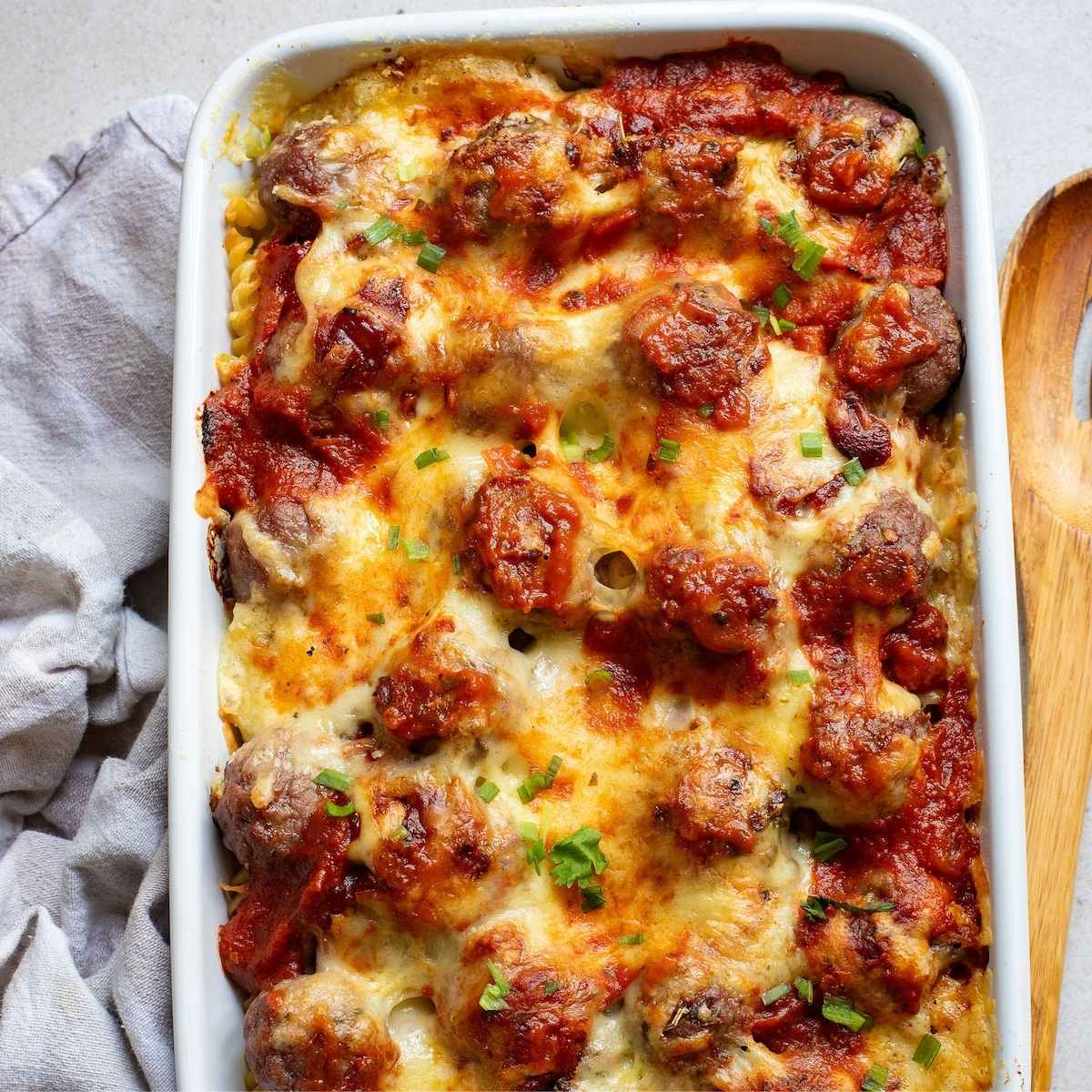 Saucy meatballs and pasta covered in cheese.
