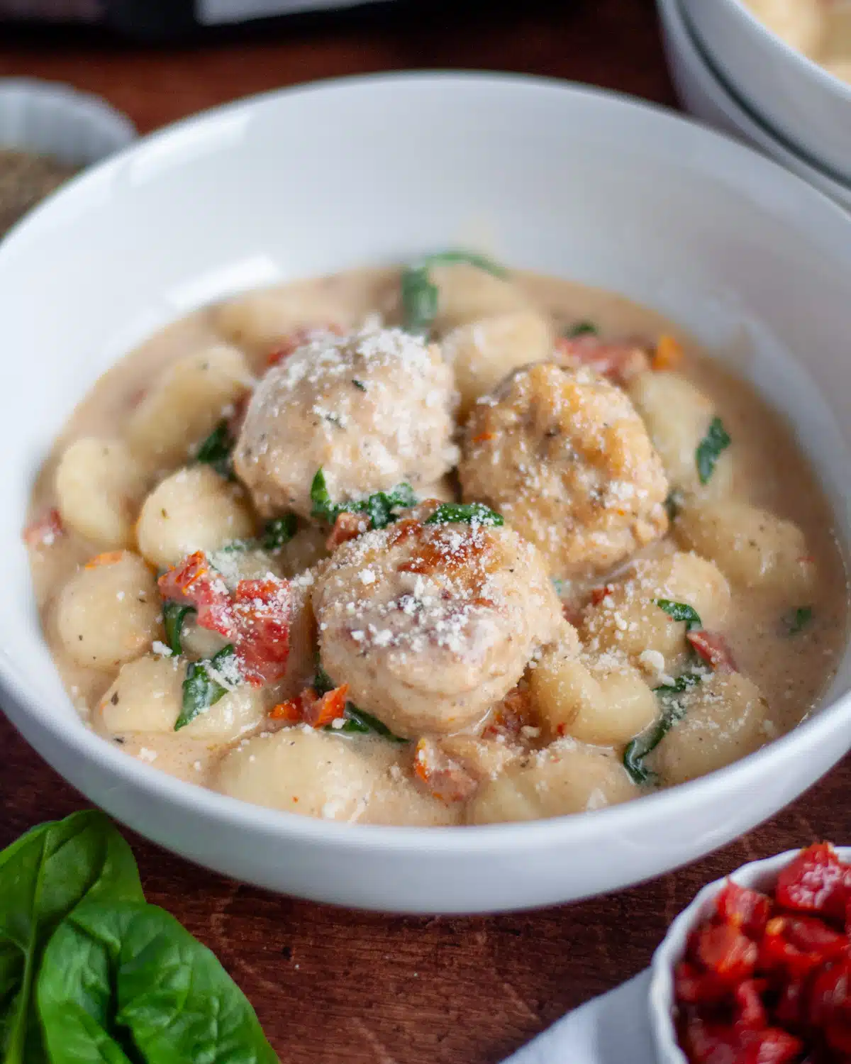 Creamy gnocchi and meatballs in a bowl.
