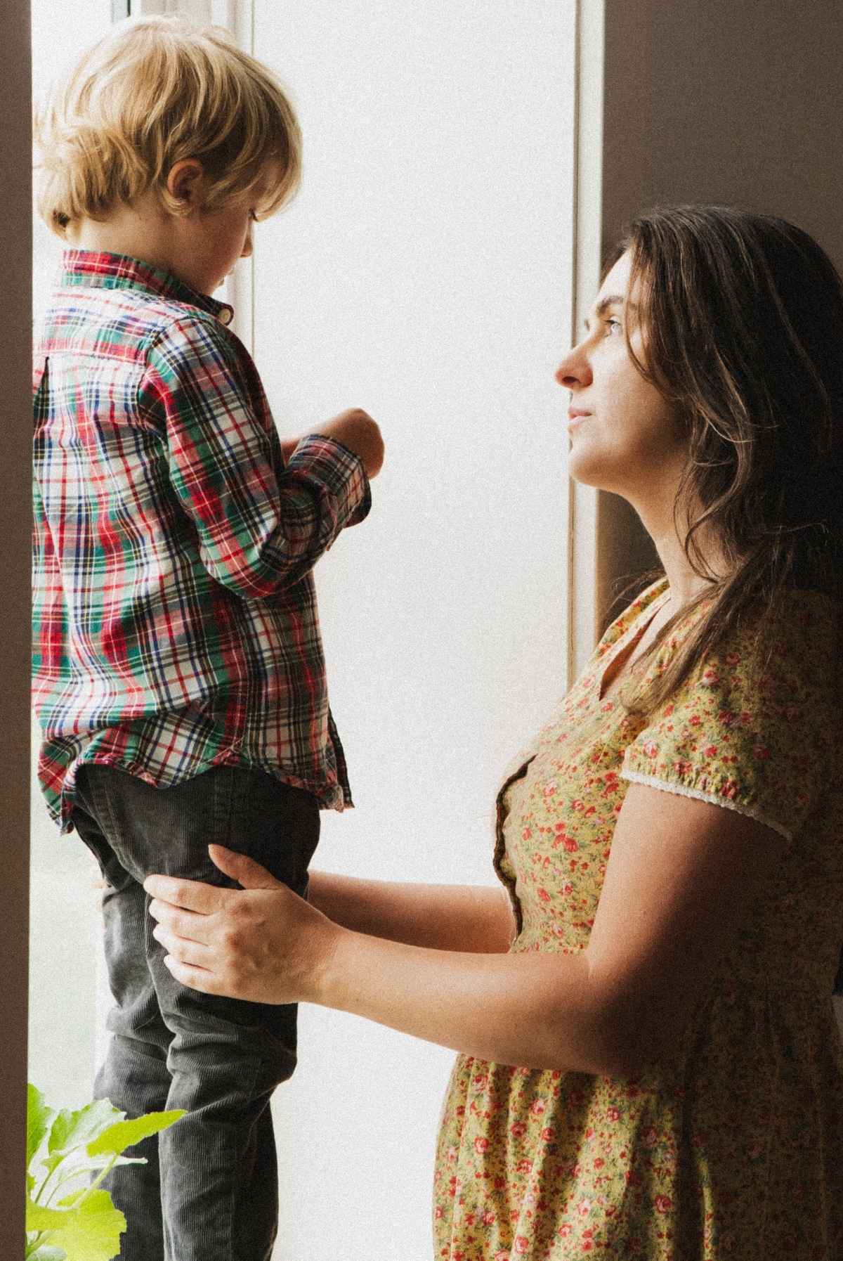 Me, standing in front of my older, blonde son who is standing at a windowsill.