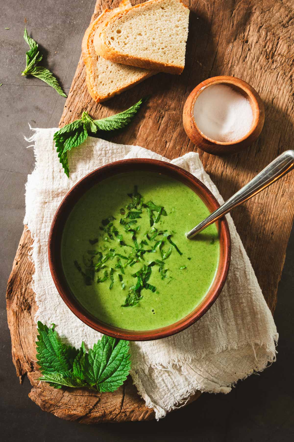 A bowl of bright green stinging nettle soup with bread on the side.