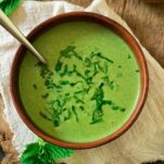 A bowl of bright green stinging nettle soup with bread on the side.