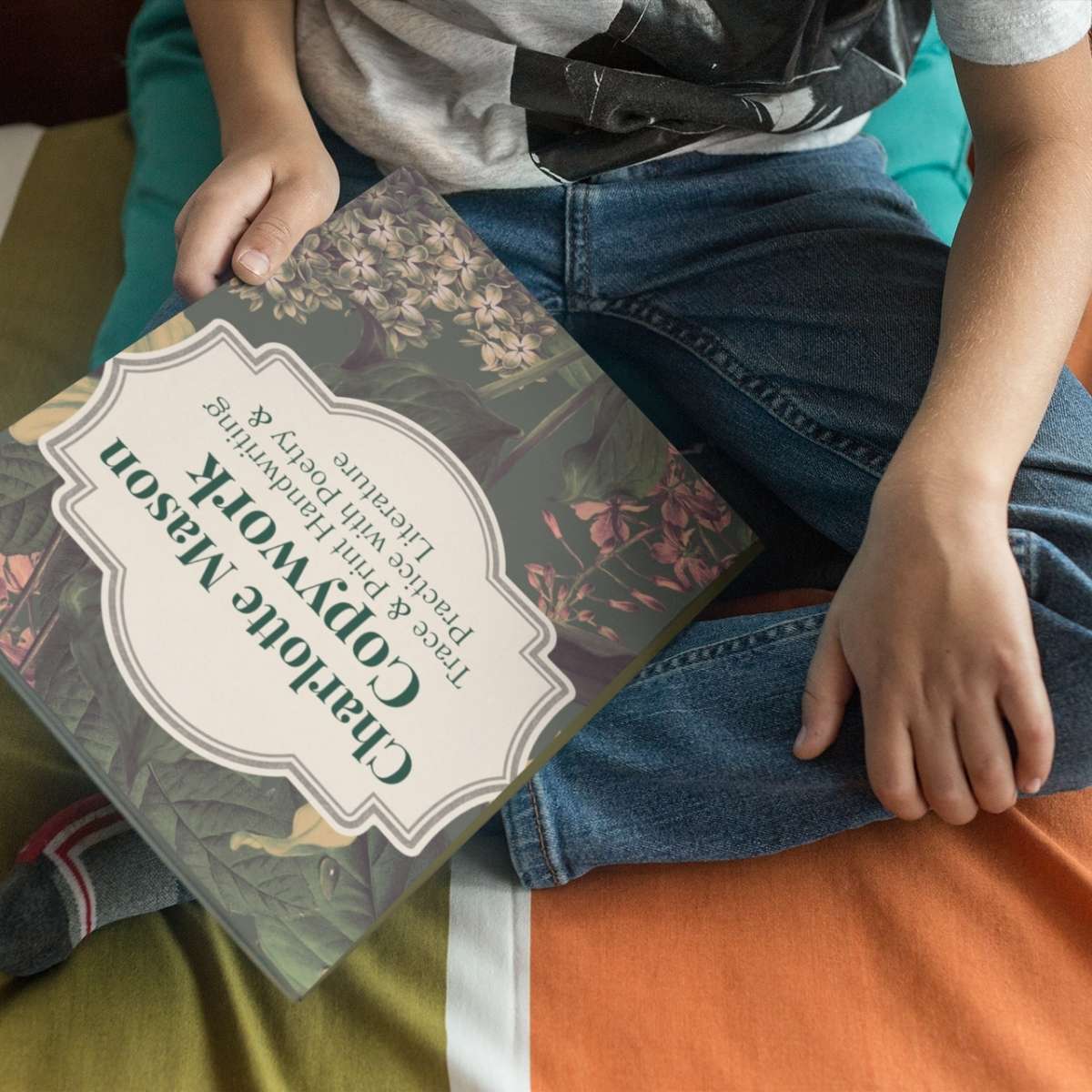 A copy of 'Charlotte Mason Cursive Copywork' by Jana Dziak held by a little boy.