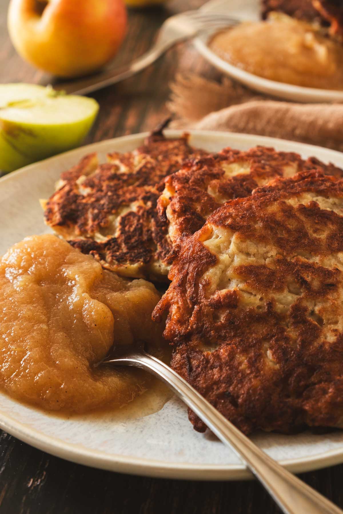 A platter of crispy, golden, round German potato pancakes served with a side of applesauce.