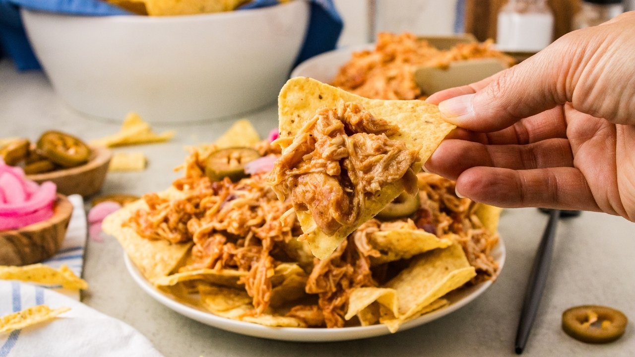 A platter of natcho chips topped with the saucy BBQ shredded chicken.