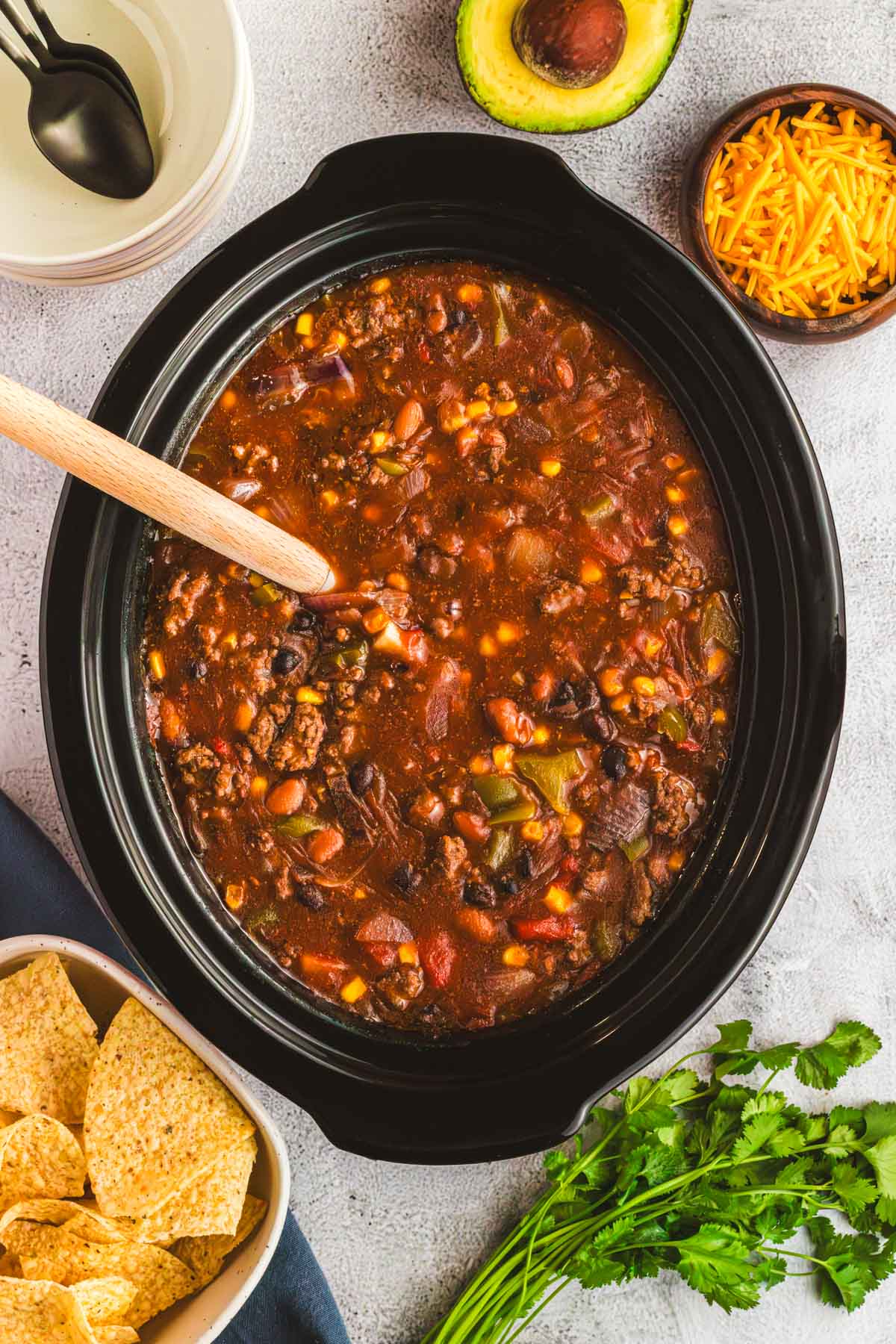 A Crock Pot slow cooker full of meaty chili with vegetables and beans.