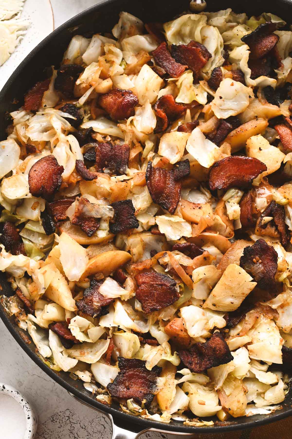 A skillet full of finished fried cabbage and bacon.