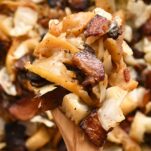 A wooden spoon full of fried cabbage and bacon.