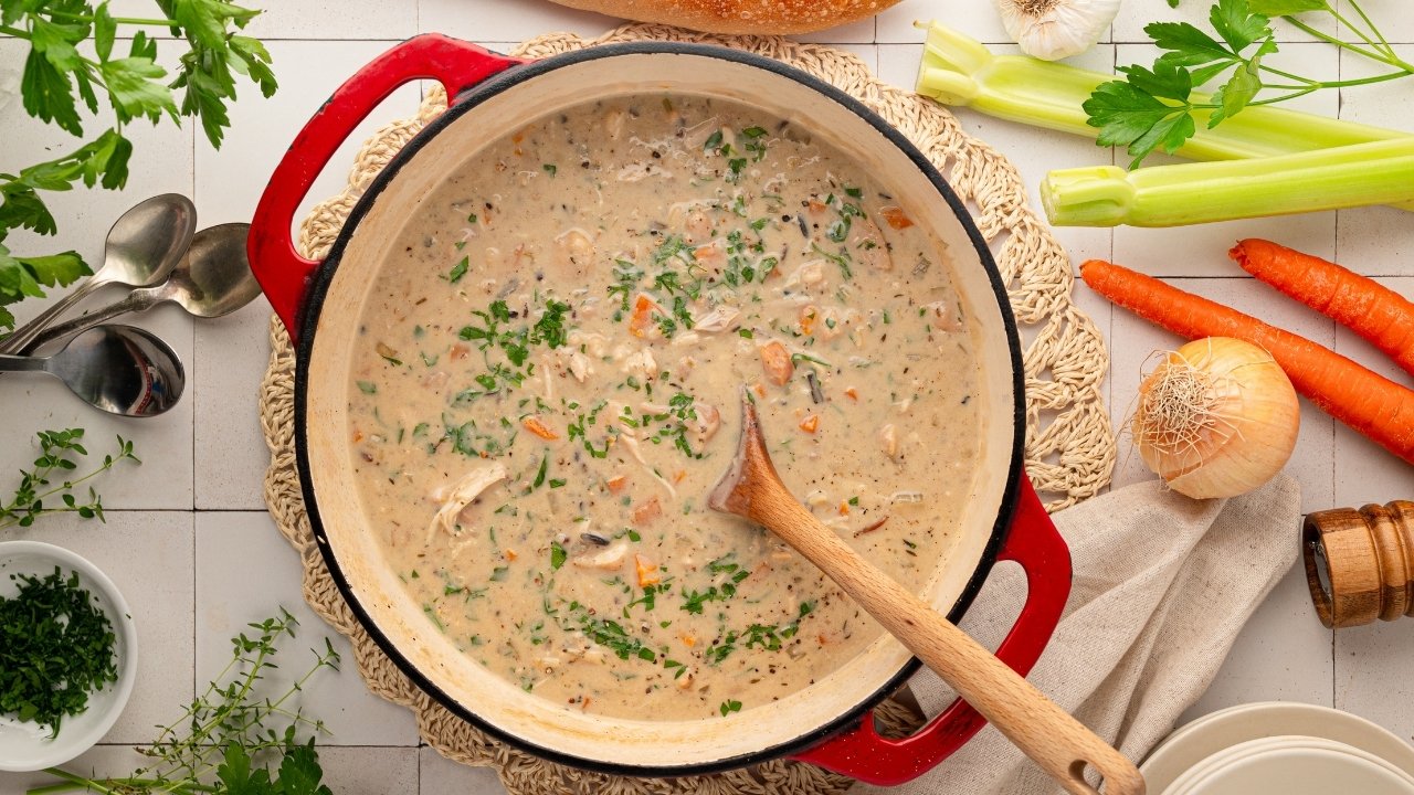A large pot of creamy chicken soup with wild rice and vegetables.