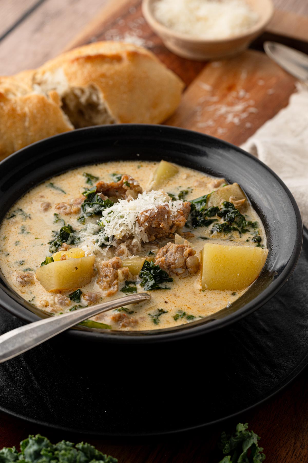 A bowl of sausage, potato and kale soup with Italian sausage, chunks of potatoes, and fresh kale in a creamy Parmesan broth, topped with freshly grated Parmigiano Reggiano.