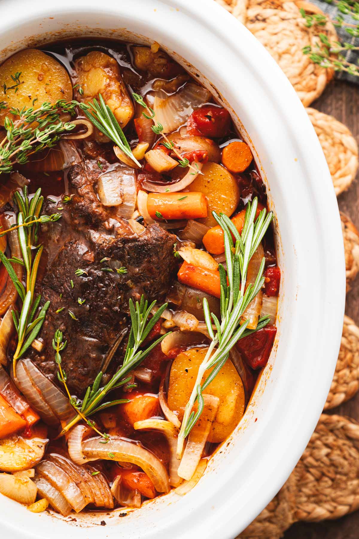 Finished slow cooker beef roast with baby yellow potatoes, carrots, and onions in a rich tomato-herb jus.